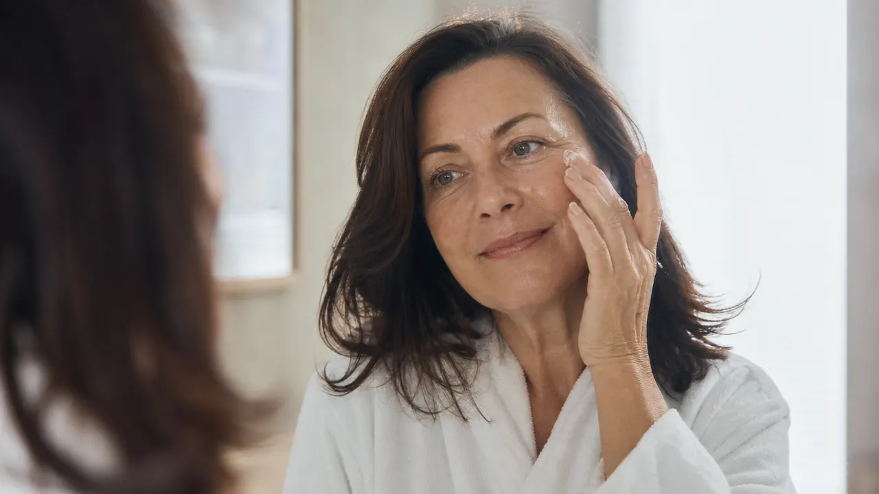 Woman patting a serum into clean glowing skin after using a facial cleansing brush